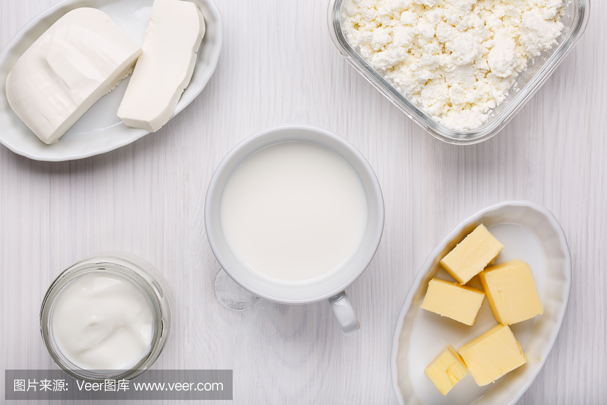 不同类型的乳制品在白色木质背景上。牛奶,软干酪,软干酪,酸奶,黄油。前视图。